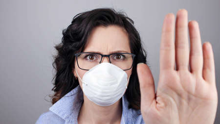 On background woman in mask focus on stretched hand. Keep distance avoid communication, healthcare concept.の写真素材
