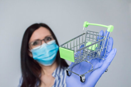 Woman wearing protection face mask against virus and glasses. Woman in a mask holding shopping cart. Medical mask, Close up shot, Select focus, Prevention from covid19の写真素材