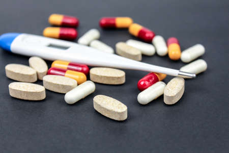Medicine pills, tablets and thermometr on black background. Pharmaceutical conceptの写真素材