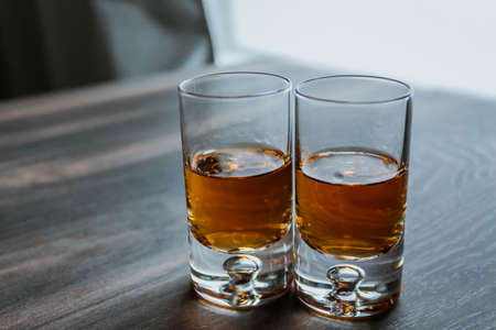Two shot glasses with whiskey on a wooden backgroundの写真素材