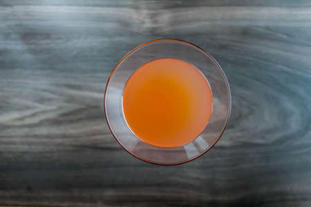 Orange fresh coctail juice in glass up view on wodden background.の写真素材