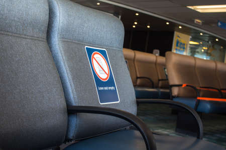 Perspective view of empty seats in the airport with social distancing regulation sign for COVID-19 epidemic awareness. Selective focus.の写真素材