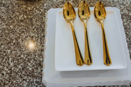 A elegant empty white plate, golden spoons on wooden table. Kitchen cutlery set.の写真素材