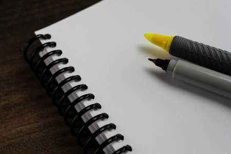 Spiral notepad paper with highlighter and pen on the wooden background. Space for textの写真素材