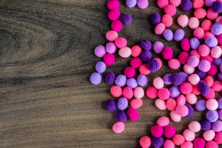 Colorful pink and purple pom pom on dark wood backgroundの写真素材