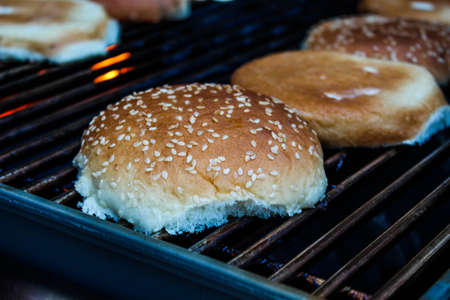 Grilled hamburger buns with sesame seeds in a metal bowl.の写真素材