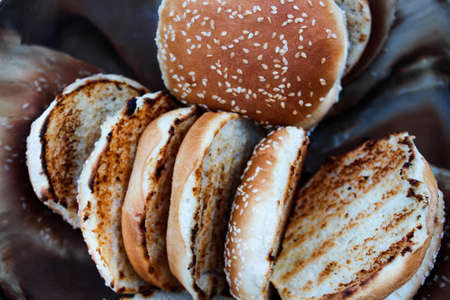 Grilled hamburger buns with sesame seeds in a metal bowl.の写真素材