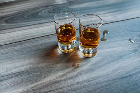 Two shot glasses with whiskey on a wooden backgroundの写真素材