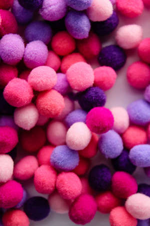 Round pink and purple fluffy balls pompoms on wooden background. Bunch of poppomsの写真素材