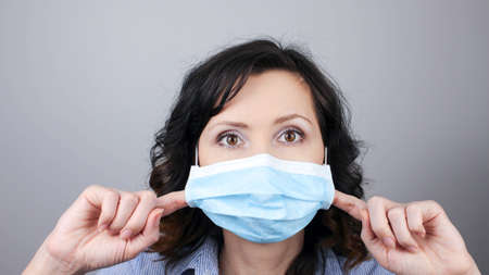 Woman wearing protection face mask against coronavirus. Woman in pulling mask away. Cannot breath. Removing face mask with fingers. Medical mask, Close up shot, Select focus, Prevention from covid19の写真素材