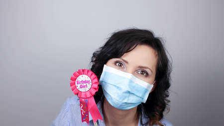 Woman wearing protection face mask against coronavirus. Woman in a mask with party supply. Birthday girl. Medical mask, Close up shot, Select focus, Prevention from covid19の写真素材