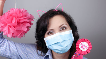 Woman wearing protection face mask against coronavirus. Woman in a mask with party supply. Happy birthday girl with cat ear headband. Medical mask, Close up shot, Select focus, Prevention from covid19の写真素材