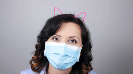 Woman wearing protection face mask against coronavirus. Woman in a mask and cute headband with cat ears.の写真素材