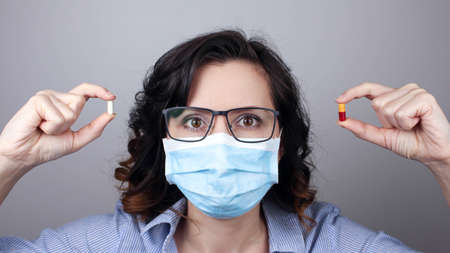 Woman in a mask showing medicine pill, vaccine. Medical mask, Close up shot, Select focus, Prevention from covid19の写真素材