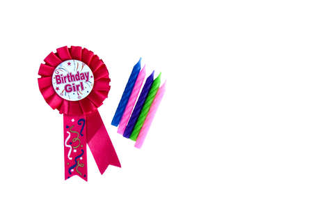 Pink birthday rosette with candles. Happy birthday wishes for a girl on a pink badge on white background. Colorful candlesの写真素材