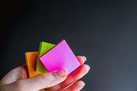 Hand with colorful notes on black backgroundの写真素材