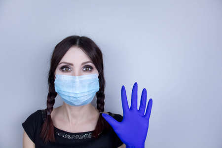 Woman wearing protection face mask against coronavirus. Woman in a mask looking shocked or worried with hand up. Medical mask, medical gloves, Close up shot, Select focus, Prevention from covid19の写真素材