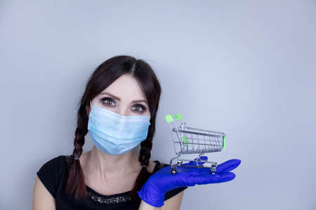 Woman wearing protection face mask against coronavirus. Woman in a mask and holding shopping cart. Medical mask, Close up shot, Select focus, Prevention from covid19の写真素材
