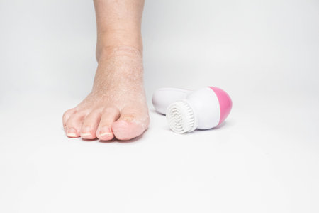 Beautiful barefoot female dry skin feet with a set of the pedicure tools on whiteの写真素材
