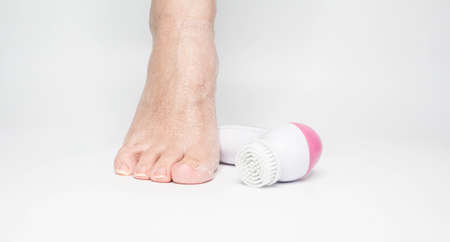 Beautiful barefoot female dry skin feet with a set of the pedicure tools on whiteの写真素材