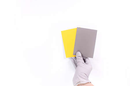 Women's hands hold swatches of the trendy colors - illuminating yellow and ultimate grey. Selection of year 2021 colors for design of clothes, interiors, websites and publications. Flat lay.の写真素材
