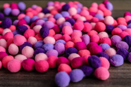 Round pink and purple fluffy balls pompoms on wooden background. Bunch of poppomsの写真素材