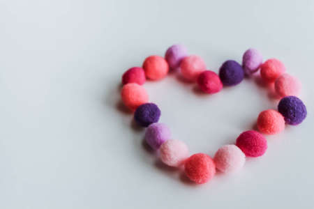 A beautiful big heart made of soft pom-poms against a light background. Heart love, love background, place for textの写真素材