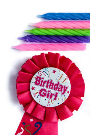 Pink birthday rosette with candles. Happy birthday wishes for a girl on a pink badge on white background. Colorful candlesの写真素材