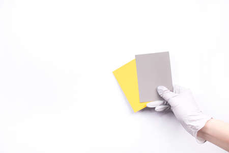 Women's hands hold swatches of the trendy colors - illuminating yellow and ultimate grey. Selection of year 2021 colors for design of clothes, interiors, websites and publications. Flat lay.の写真素材