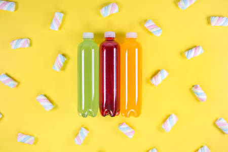 Bottles of orange, green, red smoothie on yellow background. Top view. Detox summer drink. Healthy fresh juice bottle. Vegan and vegetarian concept.の写真素材