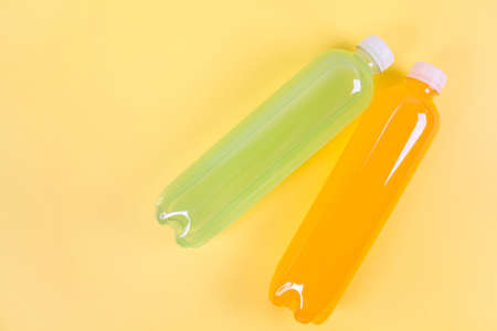 Bottles of orange, green smoothie on yellow background. Top view. Detox summer drink. Healthy fresh juice bottle. Vegan and vegetarian concept.の写真素材
