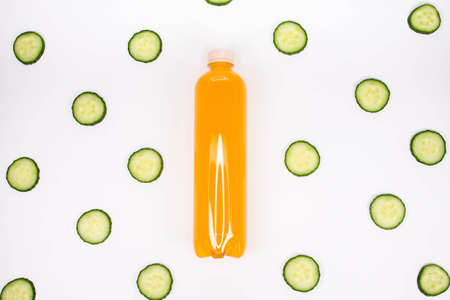 Bottle of orange smoothie on white background cucumber pattern. Top view. Detox summer drink. Healthy fresh juice bottle. Vegan and vegetarian concept.の写真素材