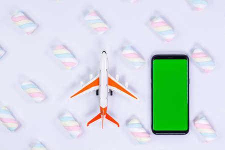 Phone mockup. Airplane model and black smartphone with blank screen. White background with twisted marshmallow pattern.の写真素材