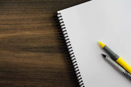 Spiral notepad paper with highlighter and pen on the wooden background. Space for textの写真素材