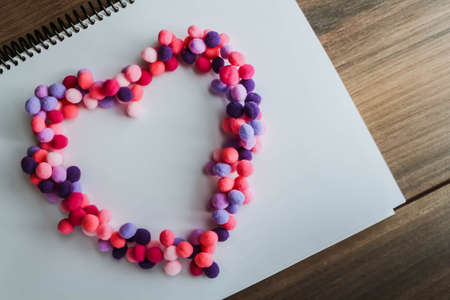 Shape of heart with colorful pompoms on whiteの写真素材