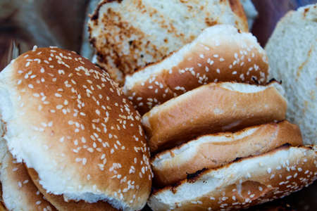 Grilled hamburger buns with sesame seeds in a metal bowl.の写真素材
