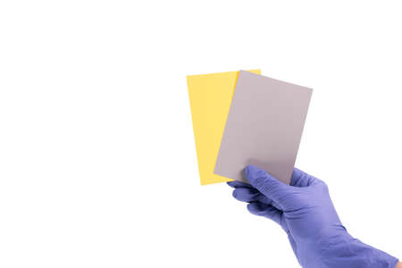 Women's hands hold swatches of the trendy colors - illuminating yellow and ultimate grey. Selection of year 2021 colors for design of clothes, interiors, websites and publications. Flat lay.の写真素材