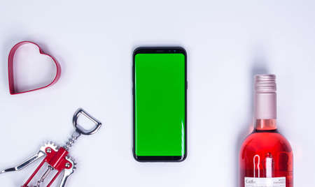 Rose and with corkscrew on white table. Mockup phone. Green screen. Top view with copy space. Space for text. Wine bottle necksの写真素材