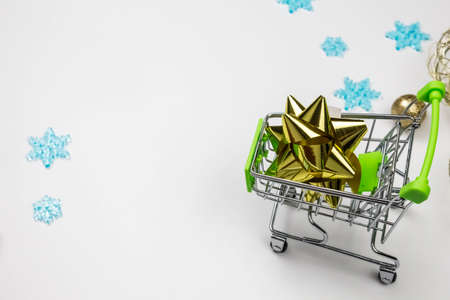 Christmas toys in the buyers basket. Full shopping cart. Balls, bells next to the shopping cart. The concept of gifts and purchases before the New Year. White backgroundの写真素材