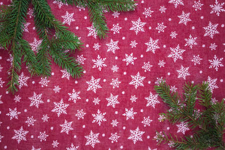 Flat lay frame with fir branches, christmas white snowflakes on red background. Space for textの写真素材
