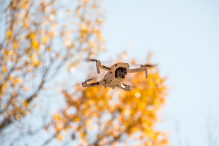 Flying drone taking pictures of autumn landscape. Blue sky, yellow leaves