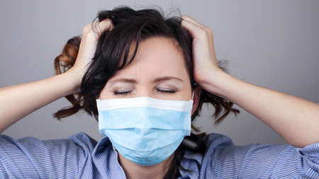 Woman wearing protection face mask against coronavirus. Cannot hear. Woman in a mask closing her ears. Medical mask, Close up shot, Select focus, Prevention from covid19の写真素材