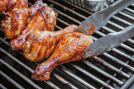 Grilled chicken on barbeque grill macro, delicious meat cooked on wooden charcoals with smokeの写真素材