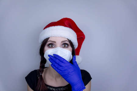 Woman wearing protection face mask against coronavirus. Woman in a mask and Christmas hat. Funny Christmas accessory. Medical mask, Close up shot, Select focus, Prevention from covid19の写真素材