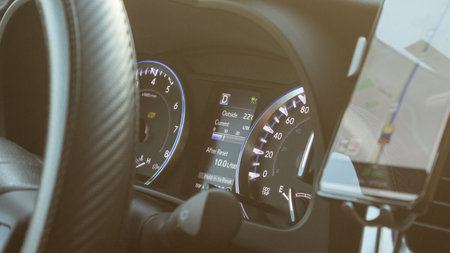 Illuminated speedometer dashboard and steering wheel of a modern car in a sun flare.の写真素材