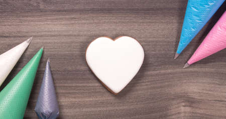 Big white heart shape cookie with icing cones for Mothers day, Womans day or Valentines Day on wooden background. Copy space.の写真素材