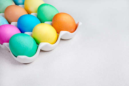 Bright colorful painted Easter eggs lying on white table. Traditional decorationの写真素材