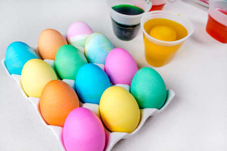 Bright colorful painted Easter eggs lying on white table. Traditional decorationの写真素材