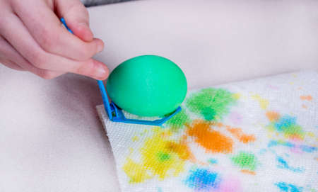 Kid hand paints eggs for easter holidays. Dyeing easter eggs at home. Child creates festive decorations.の写真素材