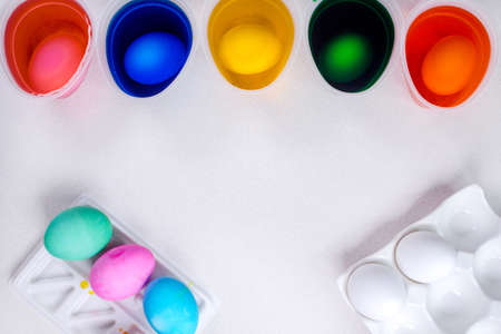 Tools for painting eggs for easter, eggs box, cups of colorful paint, easter eggs, plate, brushes and paints on the table side view.の写真素材